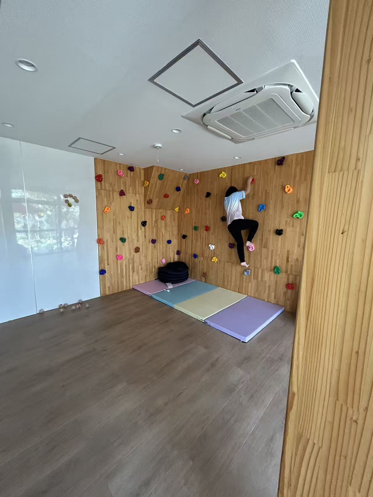 室内のボルダリングウォールを登る子ども