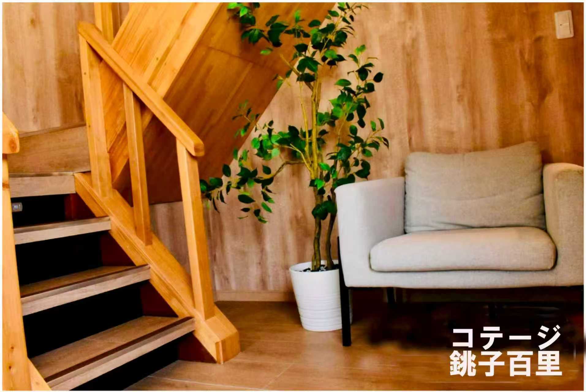 木の階段の脇に置かれた一人掛けソファと観葉植物