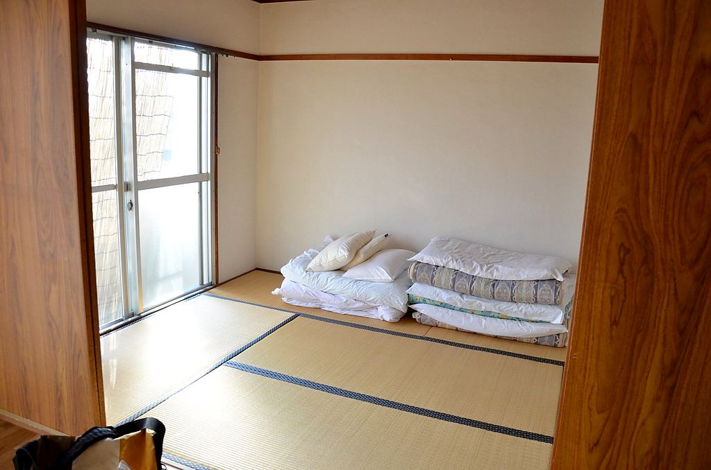 畳の部屋に、たたんだ布団が重ねてある